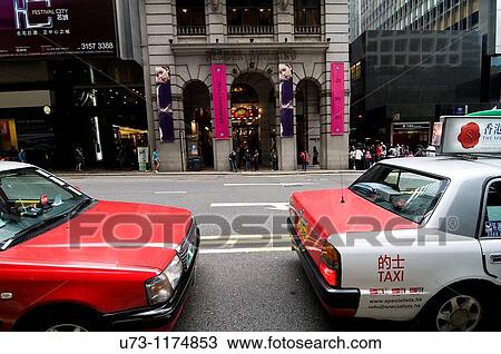 Stock Image - Taxis await passengers in downtown Hong Kong.. Fotosearch