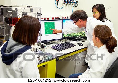 Stock Image - Teacher and students. Inverted optical microscope.. Fotosearch