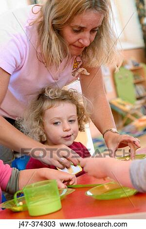 Teacher helping child at snack time at nursrey school View Large Photo Image Stock Image - Teacher helping child at snack time at nursrey school. Fotosearch
