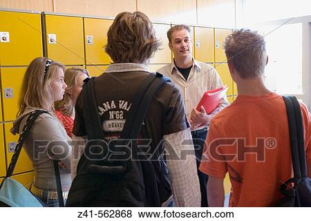 Stock Photo - Teacher talking with students in the hallway. Fotosearch