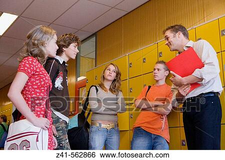 Stock Photograph - Teacher talking with students in the hallway. Fotosearch