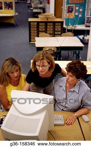 Teachers working on a project talk in a school library View Large Photo Image Stock Photograph - Teachers working on a project talk in a school library. Fotosearch