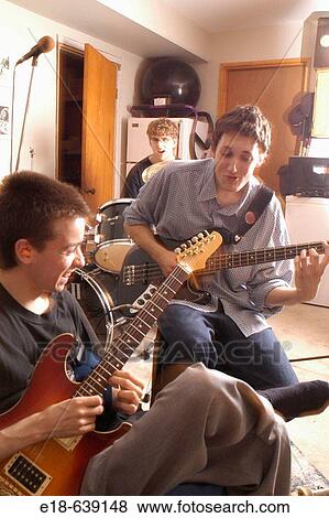 Stock Photo - Teen age boys with dreams of being rock stars, practice playing guitars and drums in the basement of their home. Vancouver, BC, Canada. Fotosearch
