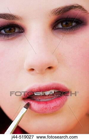 Stock Photo - Teen age girl putting makeup on lips.. Fotosearch