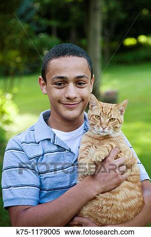Stock Photography - Teen boy holding his pet cat. Fotosearch