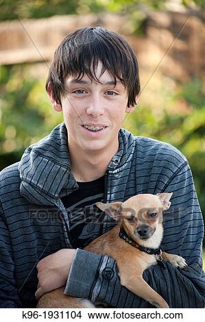 teen boy holding his pet chihuahua looking at the camera View Large Photo Image Picture - teen boy holding his pet chihuahua looking at the camera. Fotosearch