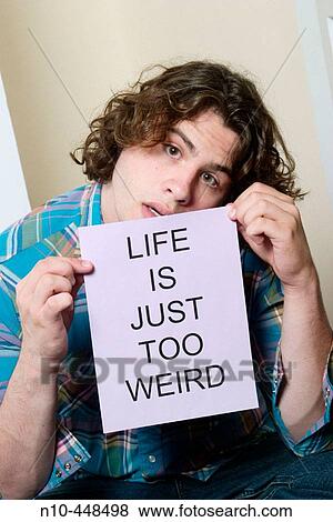 Stock Photo - Teen boy holding up a sign reading LIFE IS JUST TOO WEIRD"". Fotosearch
