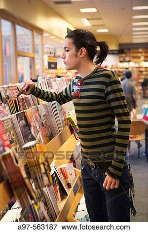 Teen boy looks through magazine rack at a bookstore. View Large Photo Image Stock Photo - Teen boy looks through magazine rack at a bookstore.. Fotosearch