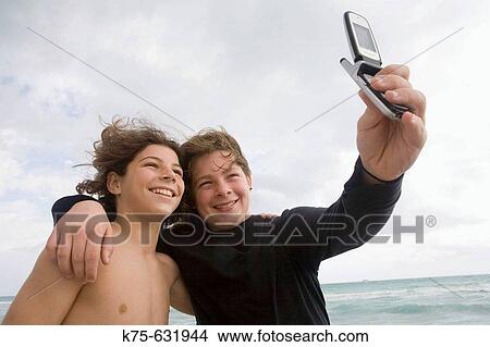 Teen brothers smile for the camera phone View Large Photo Image Picture - Teen brothers smile for the camera phone. Fotosearch