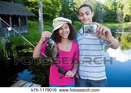 Teen couple pose for self portrait with their catch of the day View Large Photo Image Stock Photograph - Teen couple pose for self portrait with their catch of the day. Fotosearch