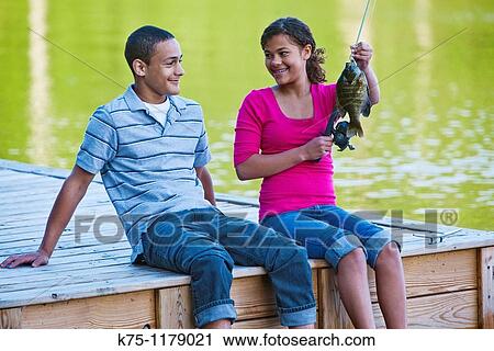 Teen couple sitting on dock with their catch of fish View Large Photo Image Stock Image - Teen couple sitting on dock with their catch of fish. Fotosearch