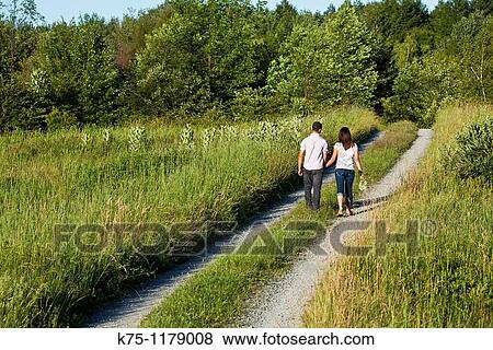Teen couple walking away on country road View Large Photo Image Stock Photo - Teen couple walking away on country road. Fotosearch