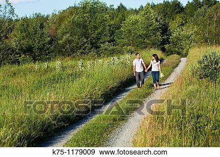 Teen couple walking holding hands on country road View Large Photo Image Stock Photo - Teen couple walking holding hands on country road. Fotosearch