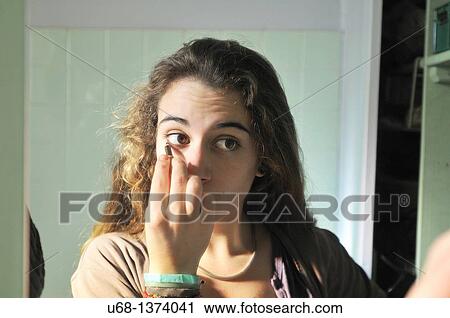 Stock Image - Teen girl applying eyeliner. Fotosearch