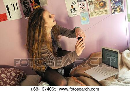 Stock Photography - Teen girl in her bedroom with laptop computer and cell phone. Fotosearch
