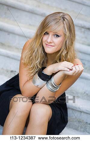 Stock Photo - Teen girl is seating on a staircase with hands held together. Fotosearch