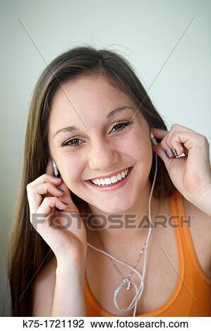 Stock Image - Teen girl listening to music on mp3 player. Fotosearch