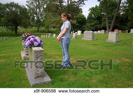 Teen girl mourns the loss of a family member The young lady gazes sadly at the headstone of the one she loves View Large Photo Image Stock Photo - Teen girl mourns the loss of a family member The young lady gazes sadly at the headstone of the one she loves. Fotosearch