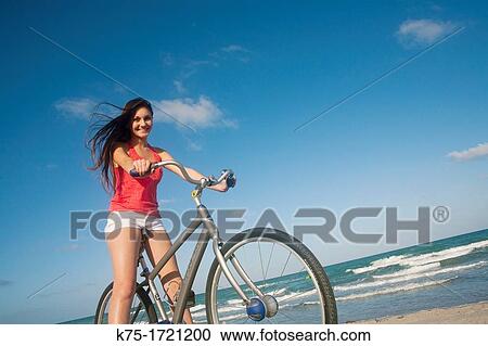 Stock Image - Teen girl riding bike at the beach. Fotosearch