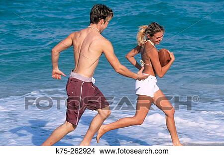 Picture - Teen girl runs with the football. Fotosearch