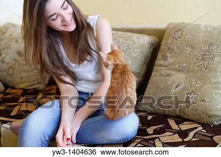 Stock Photograph - Teen girl sitting on sofa at home with kitty. Fotosearch
