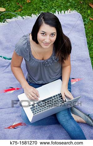 Stock Image - Teen girl studying with laptop outdoors. Fotosearch