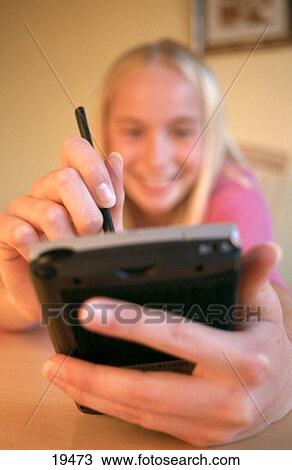 Stock Image - Teen girl using pocket personal computer. Fotosearch