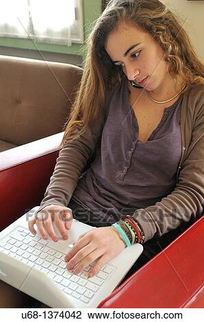 Stock Image - Teen girl using with cell phone and laptop computer. Fotosearch