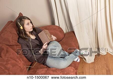 Teen girl, with a book, listening to music on her headset View Large Photo Image Stock Photo - Teen girl, with a book, listening to music on her headset. Fotosearch