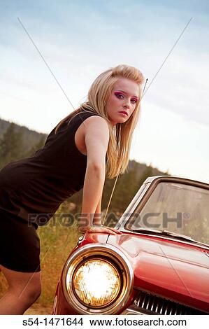 Picture - Teen girl with a red 1964 Dodge Dart.. Fotosearch