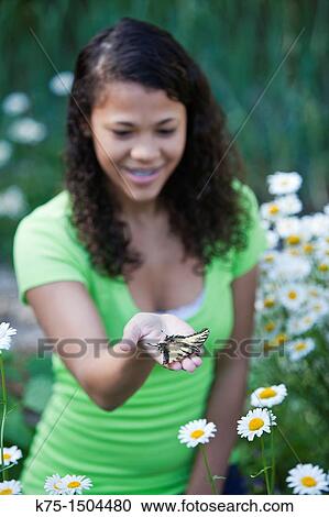 Stock Image - Teen girl with butterfly in hand. Fotosearch