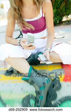 Stock Photo - Teen girl with cell phones and rollerblades. Fotosearch