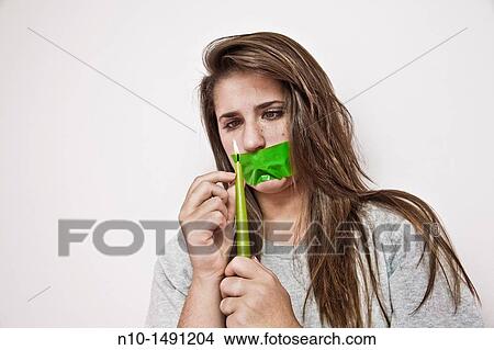 Picture - Teen girl with tape over her mouth, holding a lit candle. Fotosearch