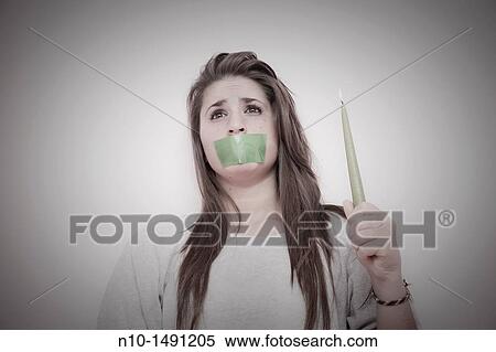 Teen girl with tape over her mouth, holding a lit candle View Large Photo Image Stock Photography - Teen girl with tape over her mouth, holding a lit candle. Fotosearch