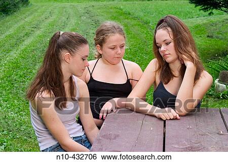 Teen girls and their young sister sitting together at a picnic table View Large Photo Image Stock Photograph - Teen girls and their young sister sitting together at a picnic table. Fotosearch