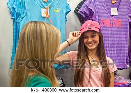 Stock Image - teen girls deciding to buy a cap. Fotosearch