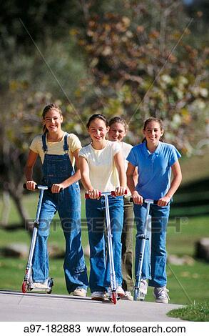 Stock Image - Teen girls riding scooters. Fotosearch