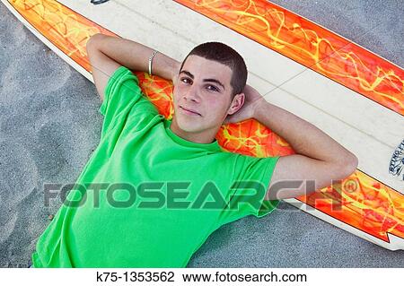 teen lying down on the beach with surfboard View Large Photo Image Stock Image - teen lying down on the beach with surfboard. Fotosearch