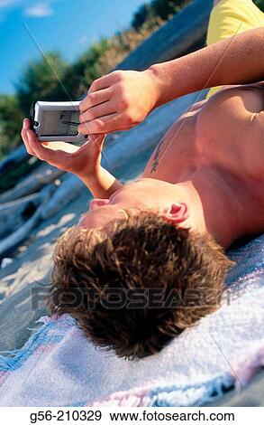 Teen lying on beach using PDA View Large Photo Image Stock Photo - Teen lying on beach using PDA. Fotosearch