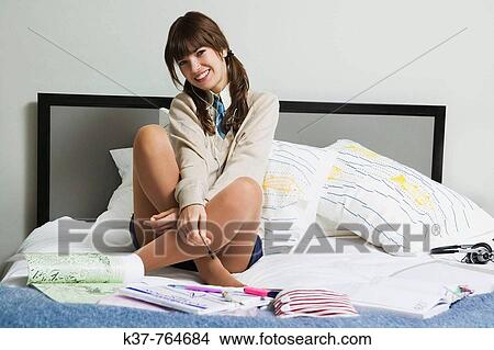 Teen schoolgirl doing homework on bed View Large Photo Image Picture - Teen schoolgirl doing homework on bed. Fotosearch