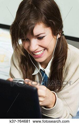 Teen schoolgirl multi-tasking - doing homework on laptop, listening to music on her MP3 player & texting on cell phone View Large Photo Image Stock Image - Teen schoolgirl multi-tasking - doing homework on laptop, listening to music on her MP3 player & texting on cell phone. Fotosearch