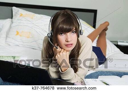 Teen schoolgirl wearing headset while working at laptop View Large Photo Image Stock Photo - Teen schoolgirl wearing headset while working at laptop. Fotosearch