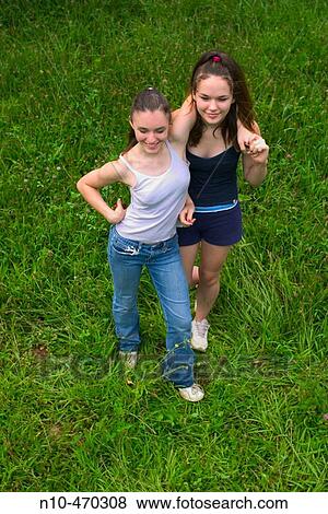 Teen sisters playing around together, the younger girl's arm around the older one's shoulders View Large Photo Image Stock Photo - Teen sisters playing around together, the younger girl's arm around the older one's shoulders. Fotosearch