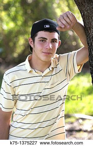 Stock Photo - teen standing next to tree. Fotosearch