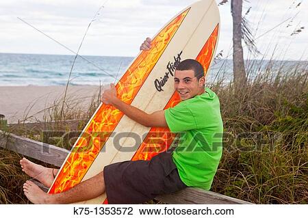 Teen surfer hugs his surfboard View Large Photo Image Stock Image - Teen surfer hugs his surfboard. Fotosearch