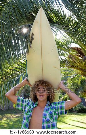 Teenage boy carrying his surfboard on his head View Large Photo Image Stock Image - Teenage boy carrying his surfboard on his head. Fotosearch