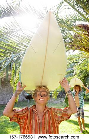 Teenage boy carrying his surfboard on his head View Large Photo Image Stock Image - Teenage boy carrying his surfboard on his head. Fotosearch