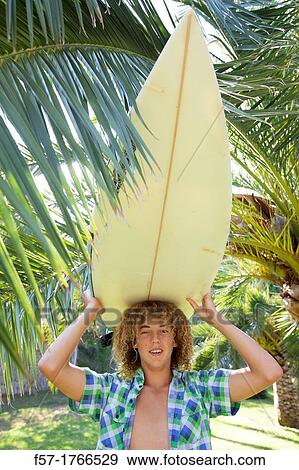 Teenage boy carrying his surfboard on his head View Large Photo Image Stock Photo - Teenage boy carrying his surfboard on his head. Fotosearch