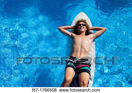 Teenage boy chilling on his surfboard View Large Photo Image Stock Photo - Teenage boy chilling on his surfboard. Fotosearch