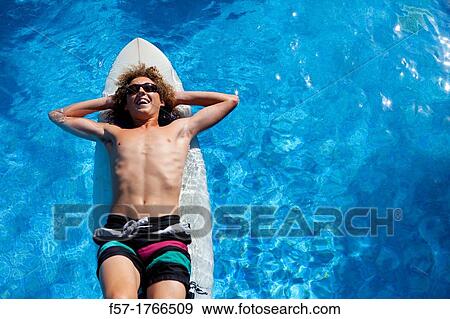 Teenage boy chilling on his surfboard View Large Photo Image Stock Photo - Teenage boy chilling on his surfboard. Fotosearch